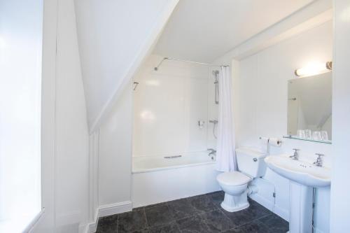 a white bathroom with a toilet and a sink at Half Moon, Sherborne by Marston's Inns in Sherborne