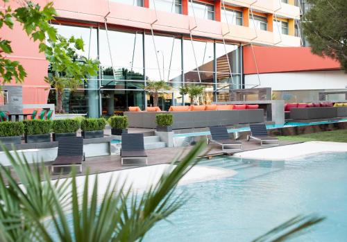 マドリードにあるホテル プエルタ アメリカのホテルの正面にプールと椅子があります。