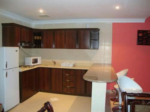 a kitchen with wooden cabinets and a white refrigerator at شقق فيلا للشقق المخدومه in Al Khobar