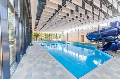 - une grande piscine avec toboggan dans un bâtiment dans l'établissement Dormio Hotel De Prins van Oranje, à Maastricht