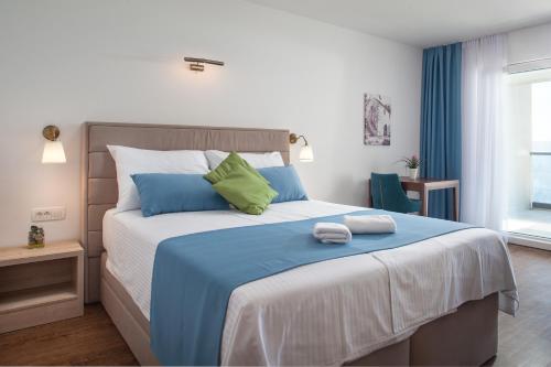 1 dormitorio con 1 cama grande con almohadas azules y verdes en Villa Cascada en Podgora
