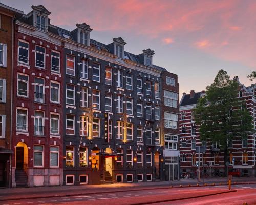 un gran edificio en una calle de la ciudad al atardecer en The ED Amsterdam, en Ámsterdam