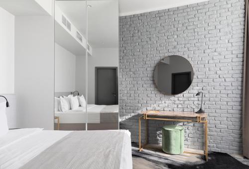 een slaapkamer met een witte bakstenen muur en een spiegel bij Hotel River Park in Cluj-Napoca