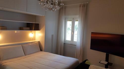 a bedroom with a bed with a chandelier and a window at Letizia Apartment in Crotone