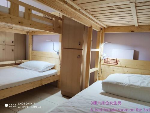 2 łóżka piętrowe w pokoju z drewnianym sufitem w obiekcie Simple life hostel w mieście Nangan