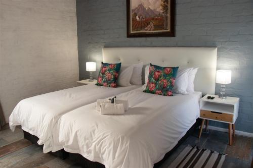 1 cama blanca grande en un dormitorio con 2 lámparas en Parkside Guesthouse, en Ladismith