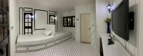 a white room with a bed and a tv at At Night in Chumphon