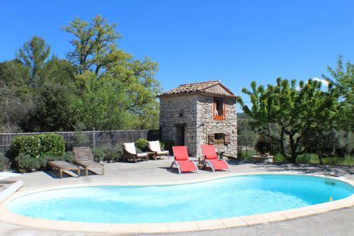 une piscine avec deux chaises et un bâtiment en pierre dans l'établissement Pierre de Lune, à Fox-Amphoux