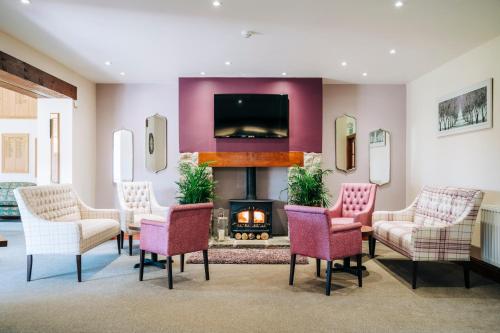 a living room with a fireplace and chairs and a tv at Mendip Spring Golf and Country Club in Churchill