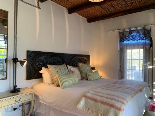 um quarto com uma grande cama branca com almofadas em The Karoo Moon Motel em Barrydale