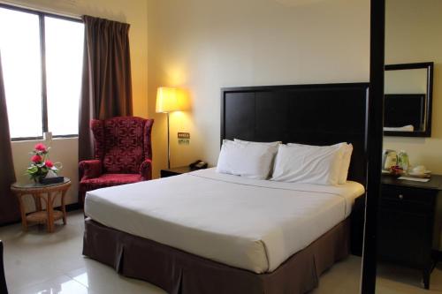 a hotel room with a large bed and a chair at Good Hope Hotel in Skudai