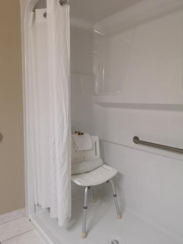 a white shower curtain and a white chair in a bathroom at Best Western Plus Red Deer Inn & Suite in Red Deer