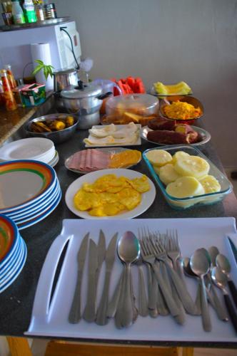una tavola con piatti di cibo, cucchiai e forchette di Espaço Revive Guesthouse e Camping - PÉ NA PRAIA a Maragogi