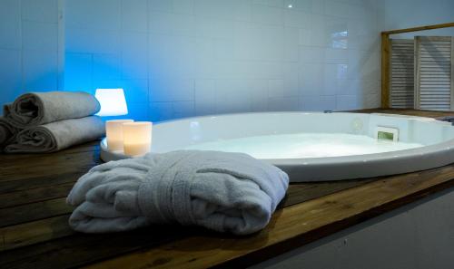 a bathroom with a bath tub with a towel and a candle at Le Grand Hotel de la Plage in Biscarrosse-Plage