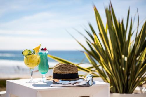 un sombrero y dos vasos en una mesa en la playa en Le Grand Hotel de la Plage, en Biscarrosse-Plage