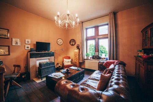 a living room with a leather couch and a fireplace at Au Plaisir in Hastière-par-delà