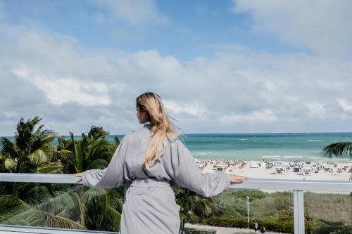 a woman standing on a balcony overlooking the beach at The Sagamore Hotel South Beach in Miami Beach