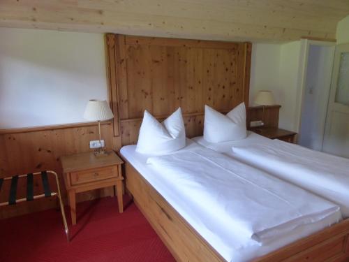 a bedroom with a large bed with white sheets and pillows at Gasthaus - Pension - Café Dörfl in Kiefersfelden