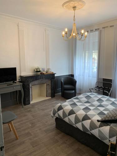 a bedroom with a bed and a desk and a television at Chambres d'hôtes de l'Eglise in Sainte-Mère-Église
