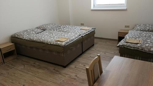 two beds in a room with a table and a window at Apartmánové ubytovanie VKF in Volkovce