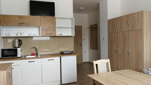 una pequeña cocina con armarios blancos y una mesa en Apartmánové ubytovanie VKF, en Volkovce