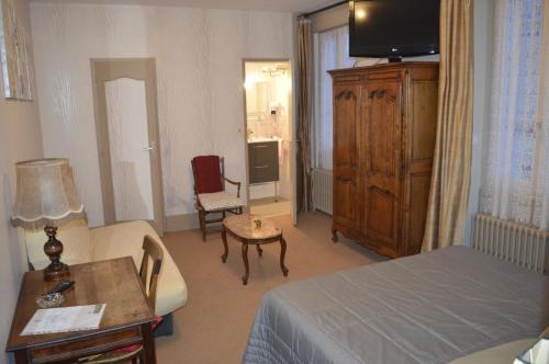 a hotel room with a bedroom with a bed and a table at Logis hôtel LE COR D'ARGENT in Argent-sur-Sauldre