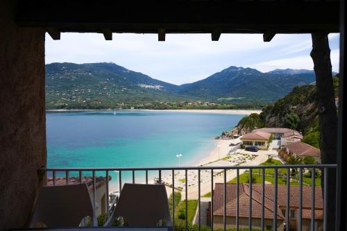 a view of a beach and the ocean from a balcony at Hôtel Sampiero in Propriano