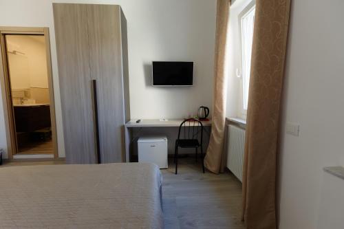 a bedroom with a desk and a television on the wall at Le Coccole in La Spezia