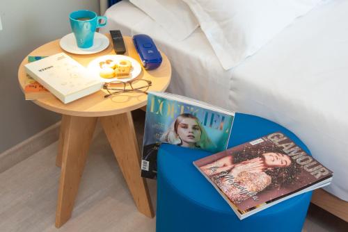 a table next to a bed with a small table with a tableasonable at Amarina Hotel in Marina di Pietrasanta