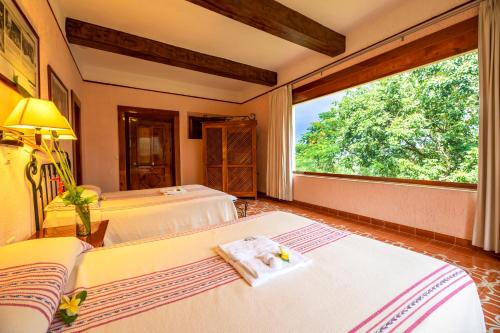 a bedroom with two beds and a large window at Hacienda Uxmal Plantation & Museum in Uxmal