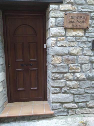 a wooden door in a stone wall with a sign at Hostal Paquita in Allepuz