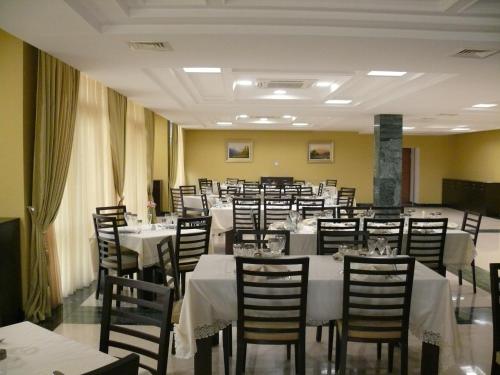 un comedor con mesas y sillas blancas en Qubek Hotel, en Balakǝn