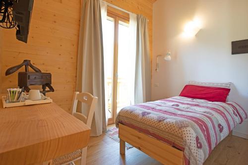 a bedroom with a bed and a table and a window at Agriturismo La Soglia Del Parco in Ranica
