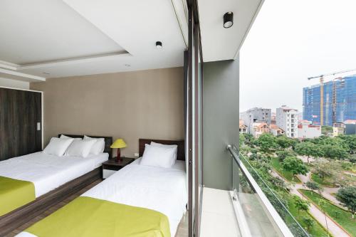 two beds in a hotel room with a balcony at Hana 2 Apartment & Hotel Bac Ninh in Bắc Ninh
