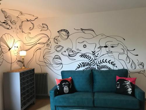 a living room with a blue couch in front of a mural at Hôtel Restaurant Gastronomique La Huchette in Mâcon