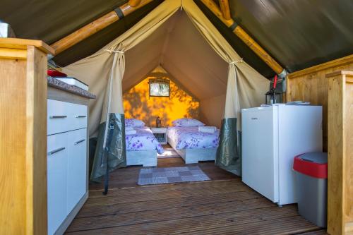 Kamp Romantik - glamping في لابين: غرفة فيها خيمة سريرين وثلاجة