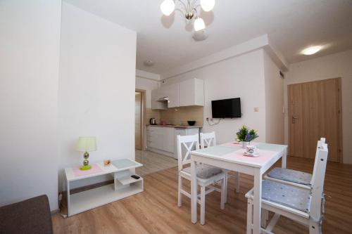 a living room with a table and chairs and a kitchen at Apartamenty Magnat in Pogorzelica