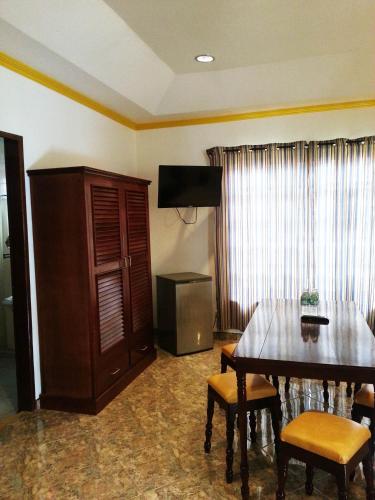 a living room with a dining room table and a television at Dolce Vita Hotel in Puerto Princesa City