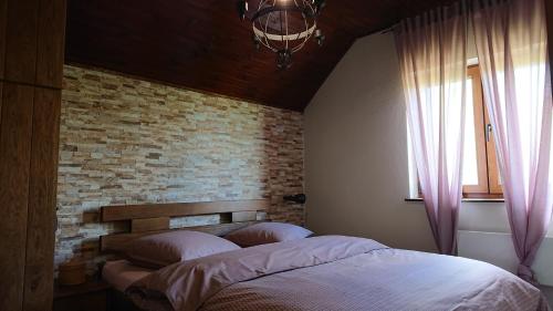 a bed in a bedroom with a brick wall at Plitvički San in Korenica