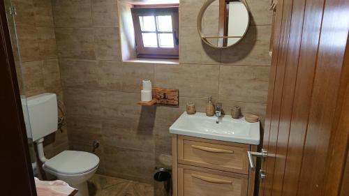 a bathroom with a sink and a toilet and a mirror at Plitvički San in Korenica