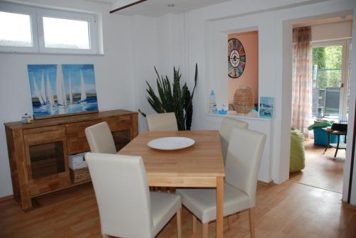 a dining room with a wooden table and white chairs at FeWo Ulamec Appartment VI in Velden am Wörthersee