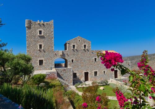 an old stone building with flowers in the foreground at Focalion Castle Luxury Suites in Pirgos Dhirou