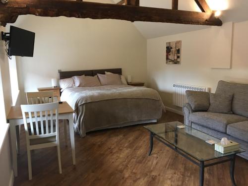 a bedroom with a bed and a couch and a table at The Stables At Harby in Melton Mowbray