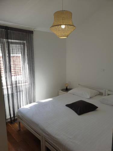 a bedroom with a white bed and a chandelier at Apartments Ivanov in Zadar