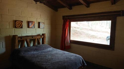 een slaapkamer met een bed en een raam bij Cabañas Tapalpa Sierra del Tecuan, Cabaña Venado in Tapalpa