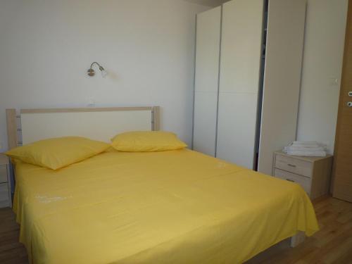 a yellow bed with two pillows in a bedroom at Apartments Kate - 20m from the beach in Brist