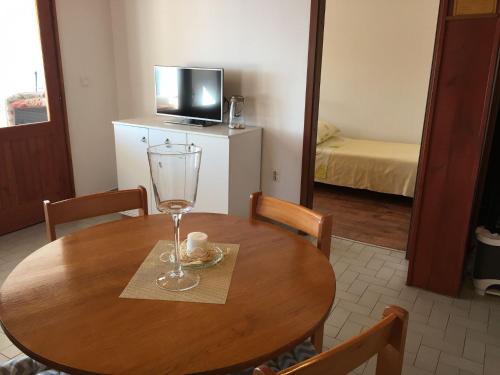 a dining room table with a wine glass and a television at Apartments Đurđa - amazing location in Sali