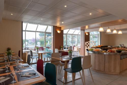 un restaurant avec des tables, des chaises et un comptoir dans l'établissement The Originals City Hôtel Marseille Aéroport, à Vitrolles