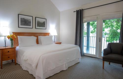 a bedroom with a bed and a chair and a window at Southbridge Napa Valley in St. Helena