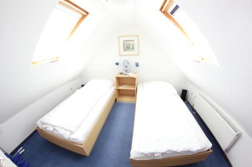 2 Betten in einem kleinen Zimmer mit 2 Fenstern in der Unterkunft Skipper in Dorum Neufeld